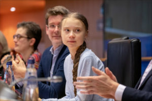 Greta Thunberg sitting at a table with other people at European Parliament.